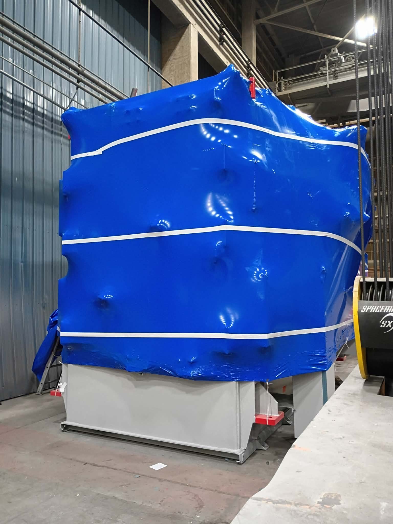 Crew member inspecting freshly applied shrink wrap on industrial machinery